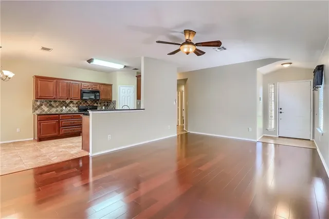 a view of a kitchen with a refrigerator a ceiling fan and wooden floor