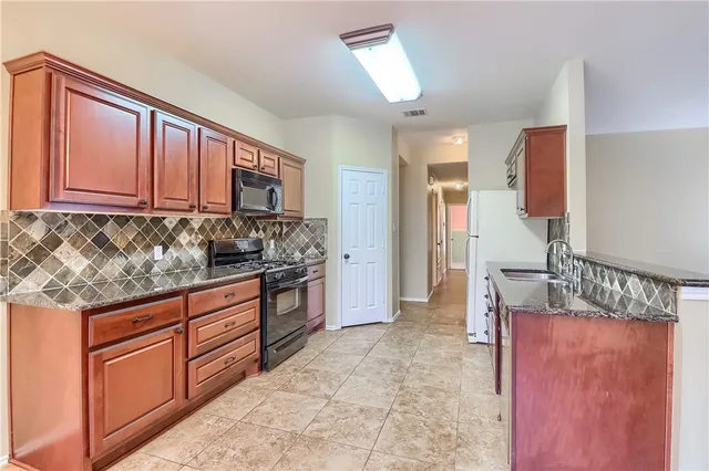 a kitchen with stainless steel appliances granite countertop a stove a sink and a refrigerator