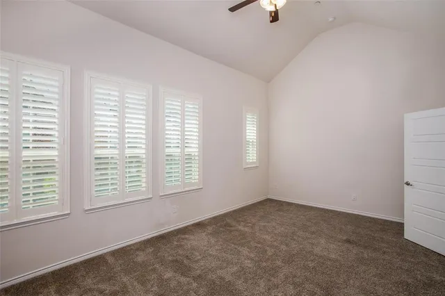 a view of an empty room with a window and a kitchen