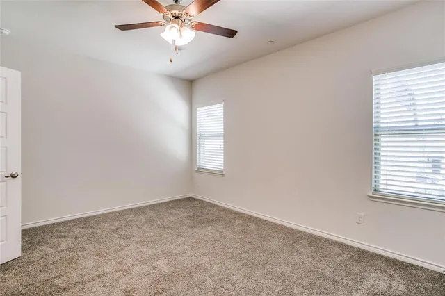 an empty room with a window and a fan