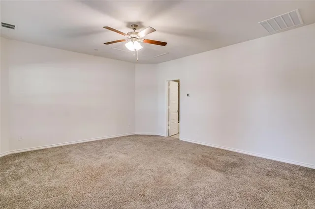 an empty room with a chandelier fan and windows