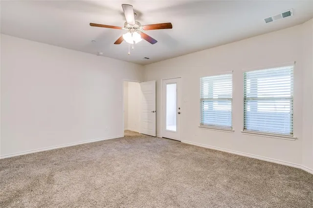 an empty room with windows and chandelier fan
