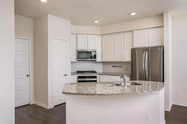 a kitchen with stainless steel appliances granite countertop a refrigerator and a stove top oven