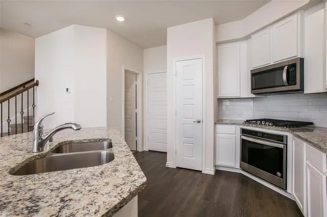 a kitchen with granite countertop a sink and a stove top oven