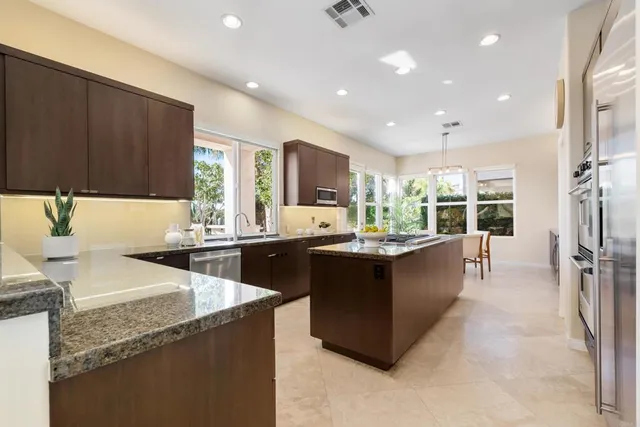 a dining room with furniture a potted plant and kitchen view