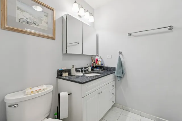 a bathroom with a granite countertop sink a toilet and a mirror