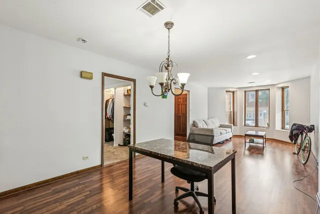 a kitchen with stainless steel appliances granite countertop a refrigerator a sink dishwasher a dining table and chairs with wooden floor