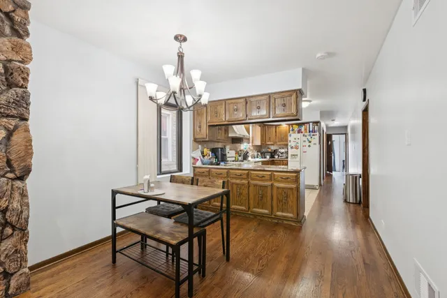 a kitchen with stainless steel appliances kitchen island granite countertop a table chairs and a refrigerator