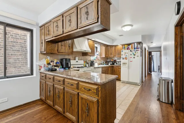 a kitchen with stainless steel appliances granite countertop a refrigerator a sink and wooden cabinets