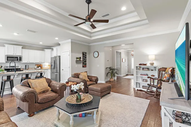 a living room with furniture kitchen view and a wooden floor