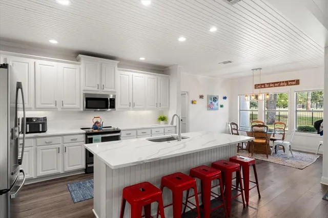 a kitchen with stainless steel appliances a white table chairs and a refrigerator