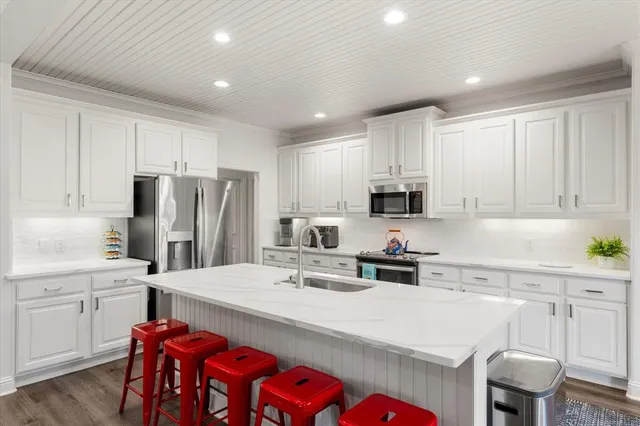 a kitchen that has a lot of white cabinets and stainless steel appliances