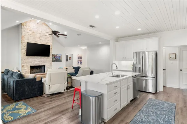 a large white kitchen with a stove a sink dishwasher a microwave oven with a dining table and chairs