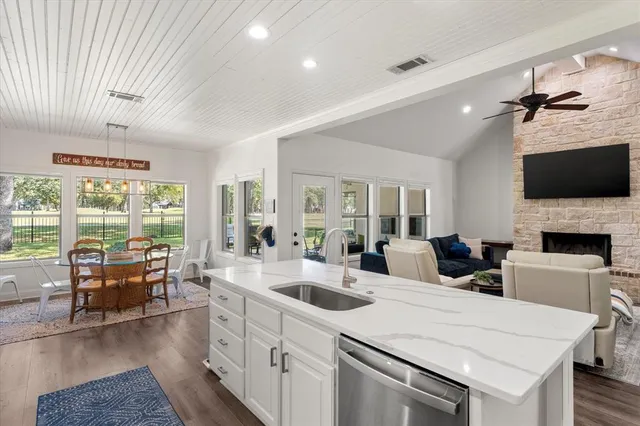 a large living room with stainless steel appliances granite countertop furniture a fireplace a flat screen tv and a large window