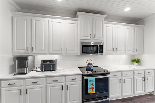 a kitchen with stainless steel appliances granite countertop white cabinets a stove top oven a sink and dishwasher