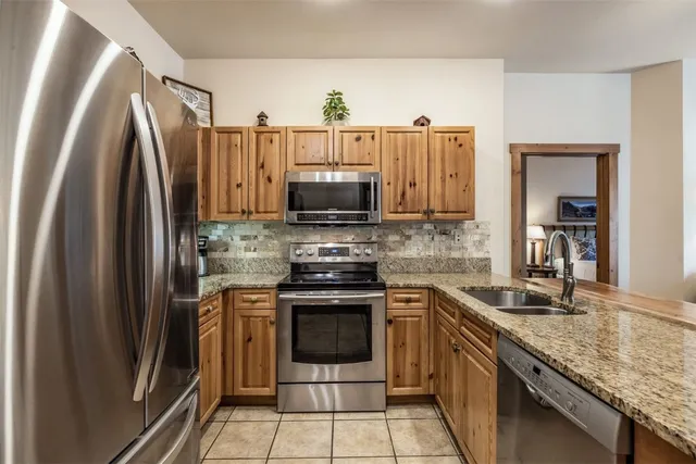 a kitchen with stainless steel appliances granite countertop a stove a refrigerator and a sink