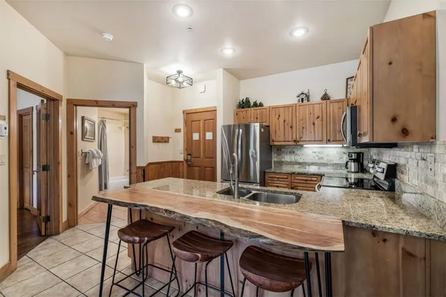 a kitchen with granite countertop a table chairs stove and refrigerator
