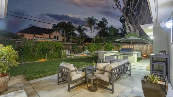 a view of a patio with couches chairs and a table and chairs under an umbrella