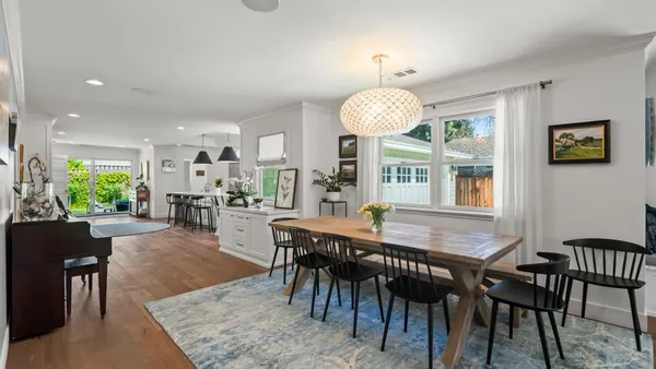 a dining room with wooden floor a chandelier a wooden table and chairs