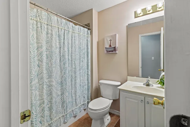 a bathroom with a granite countertop toilet and a sink