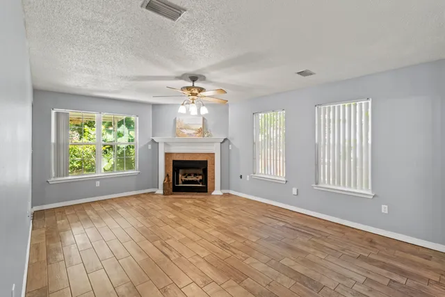 an empty room with windows fireplace and wooden floor