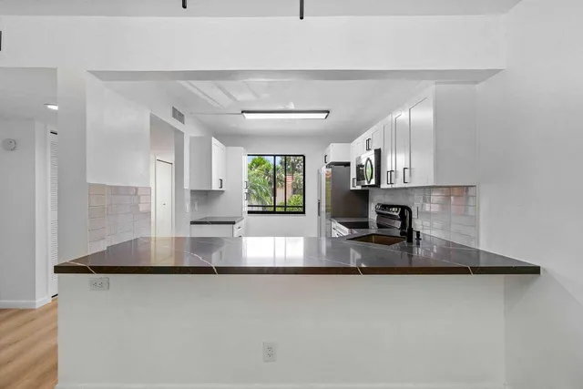 a kitchen with stainless steel appliances granite countertop a sink refrigerator and microwave