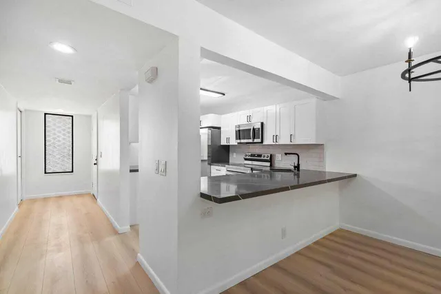a view of a kitchen with wooden floor and a ceiling fan