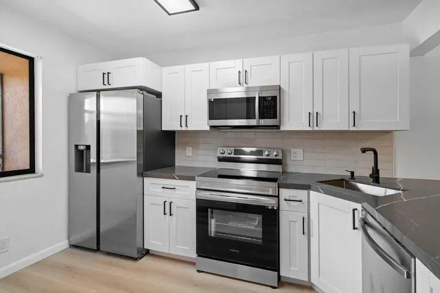 a kitchen with stainless steel appliances granite countertop a sink a stove and a granite counter tops