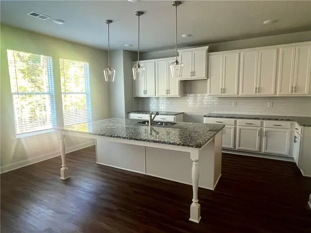 a kitchen with stainless steel appliances granite countertop a sink a stove a refrigerator and island with wooden floor