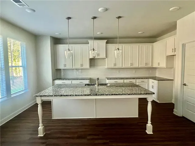 a kitchen with kitchen island granite countertop a sink cabinets and stainless steel appliances