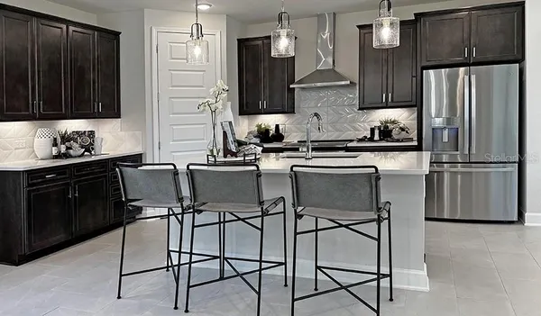 a kitchen with stainless steel appliances a refrigerator a stove a sink and chairs