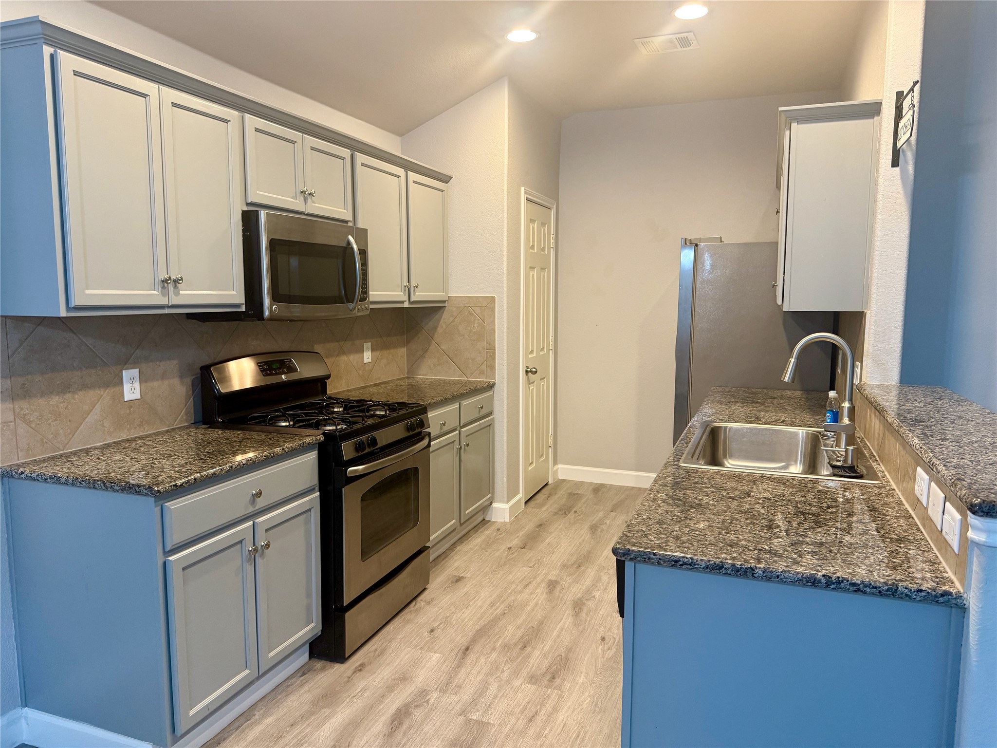 315 Nottingham Loop Kyle, TX 78640 - Photo 3 of 16 A contemporary kitchen showcasing durable granite counters and stainless steel appliances.