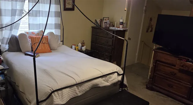 a bedroom with a bed and a flat tv screen on the dresser