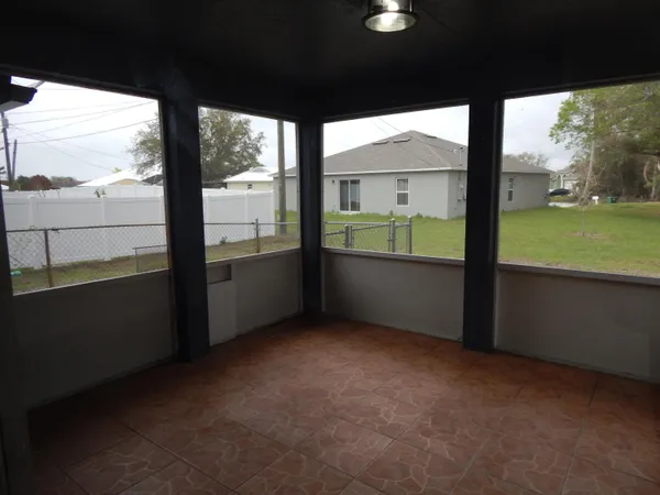 a view of an empty room with a large window and kitchen view
