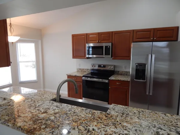a kitchen with stainless steel appliances granite countertop a refrigerator stove and microwave