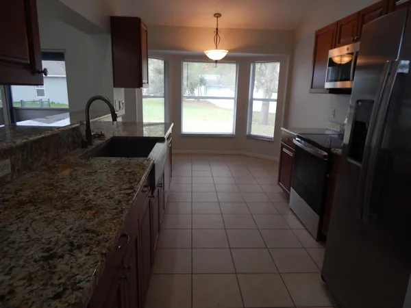 a kitchen with granite countertop a stove a sink and a refrigerator