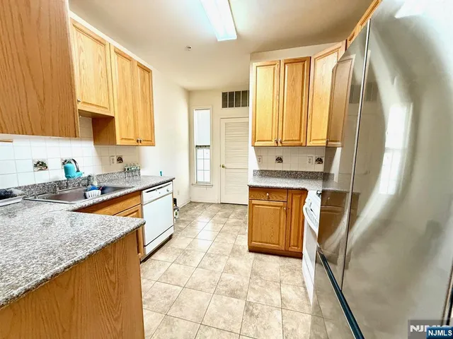 a kitchen with granite countertop a sink a counter top space and cabinets