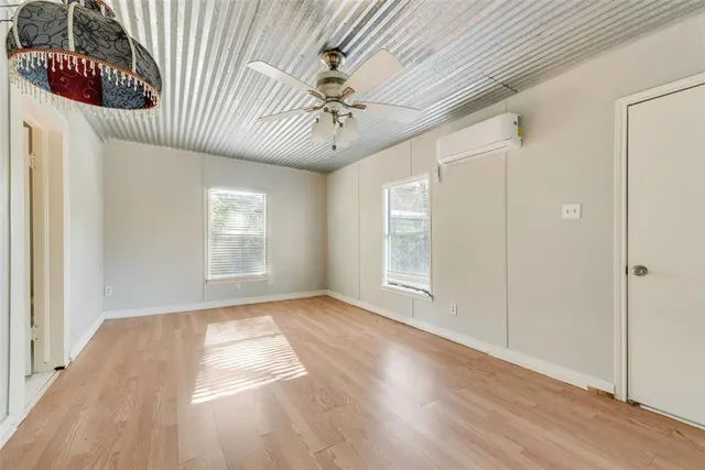 an empty room with wooden floor fan and windows