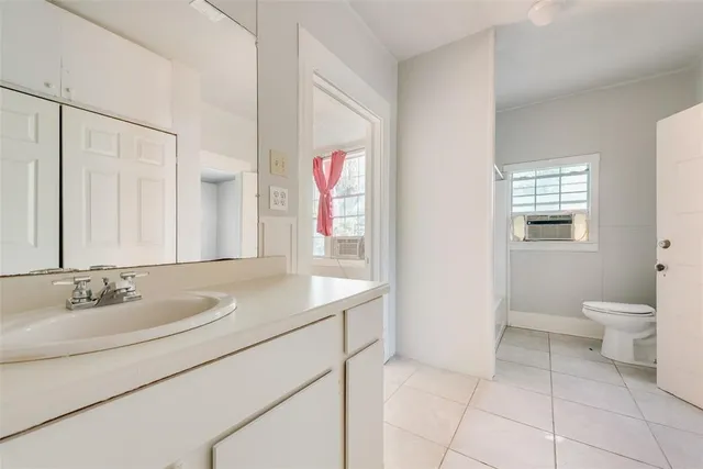 a bathroom with a granite countertop sink a toilet and a mirror