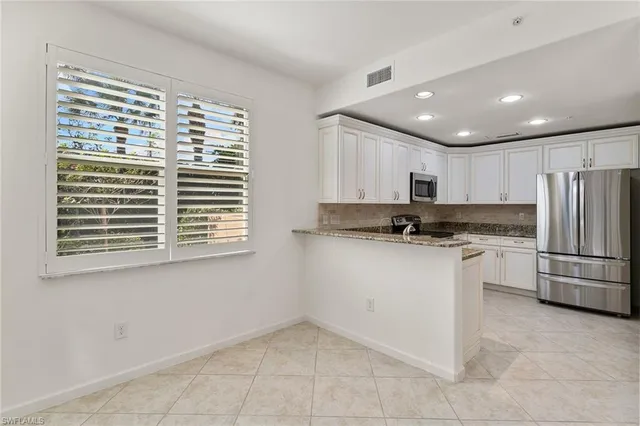 a kitchen with a refrigerator and white cabinets