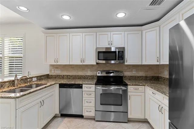 a kitchen with white cabinets appliances and a sink