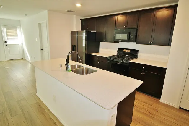 a kitchen with a sink a refrigerator and chairs