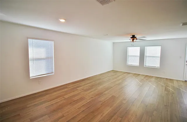 an empty room with wooden floor and windows