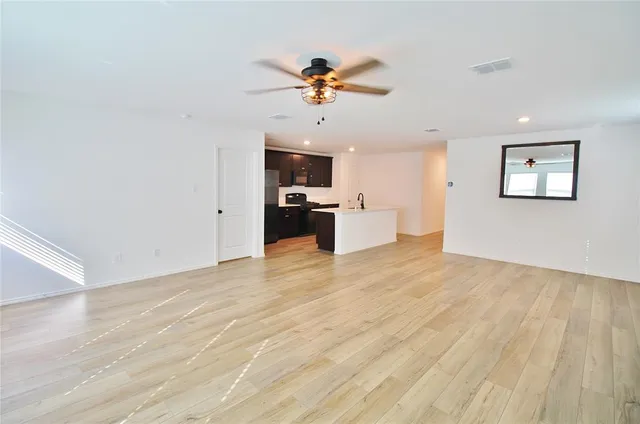 a view of a kitchen with a sink a ceiling fan and stainless steel appliances