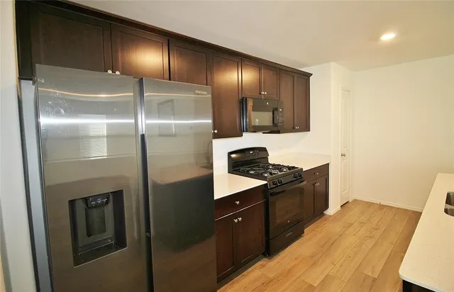 a kitchen with stainless steel appliances granite countertop a refrigerator a stove and a sink with wooden floor