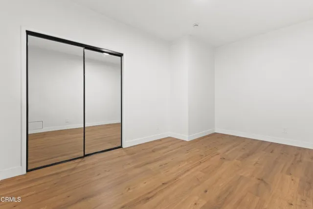 an empty room with wooden floor and mirror
