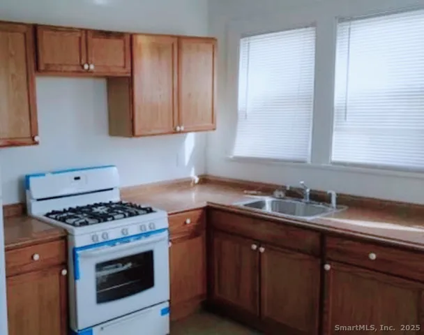 a kitchen with granite countertop a sink stove and cabinets