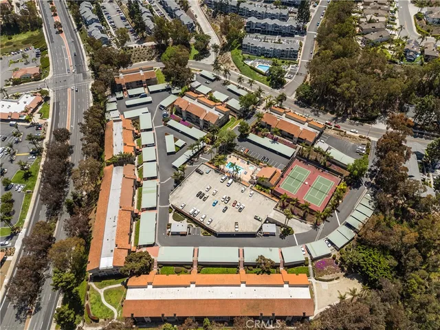 an aerial view of a residential apartment building with a yard and parking spaces