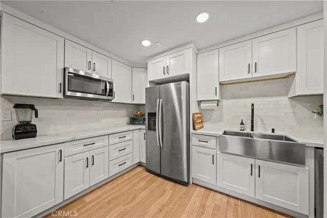 a kitchen with white cabinets white stainless steel appliances and sink