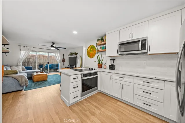 a kitchen with stainless steel appliances granite countertop a stove and white cabinets with wooden floor